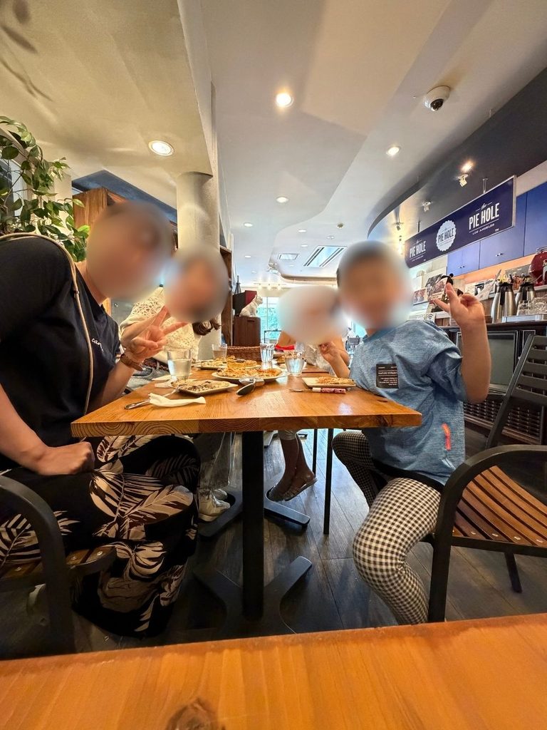 The Pie Holeでピザを食べる子どもたちとピースサイン