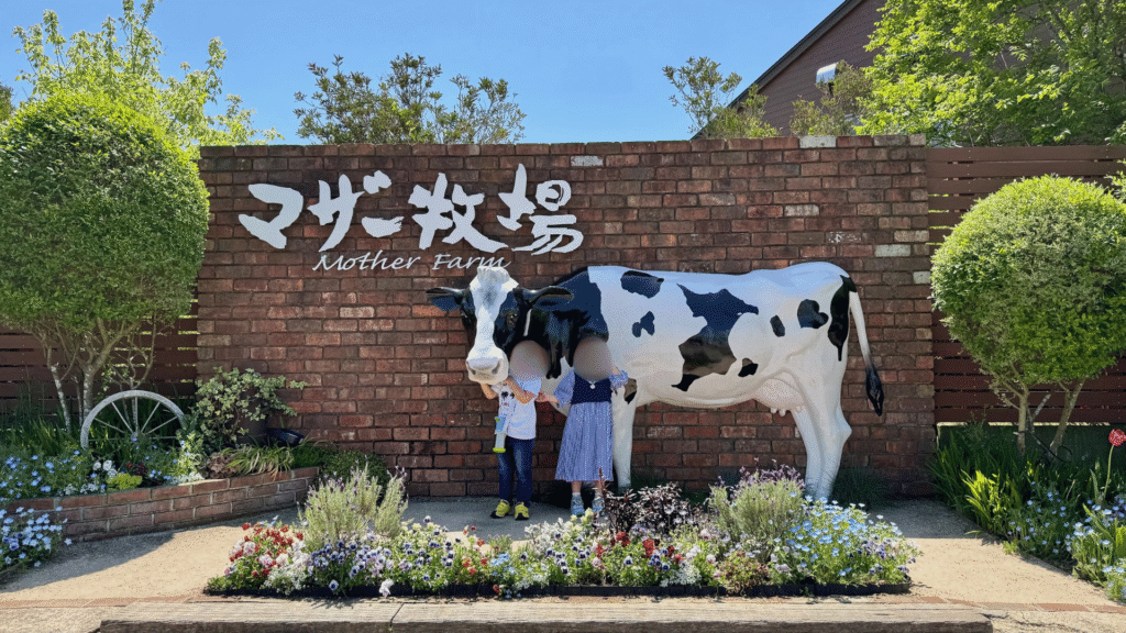 マザー牧場入り口の牛のオブジェの前で記念撮影する上の子と下の子