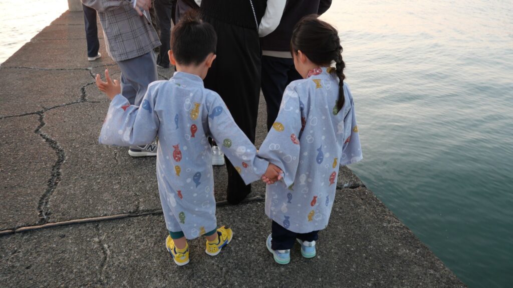 岡本桟橋で手をつなぐ子どもたち、浴衣姿で桟橋から海を眺める様子
