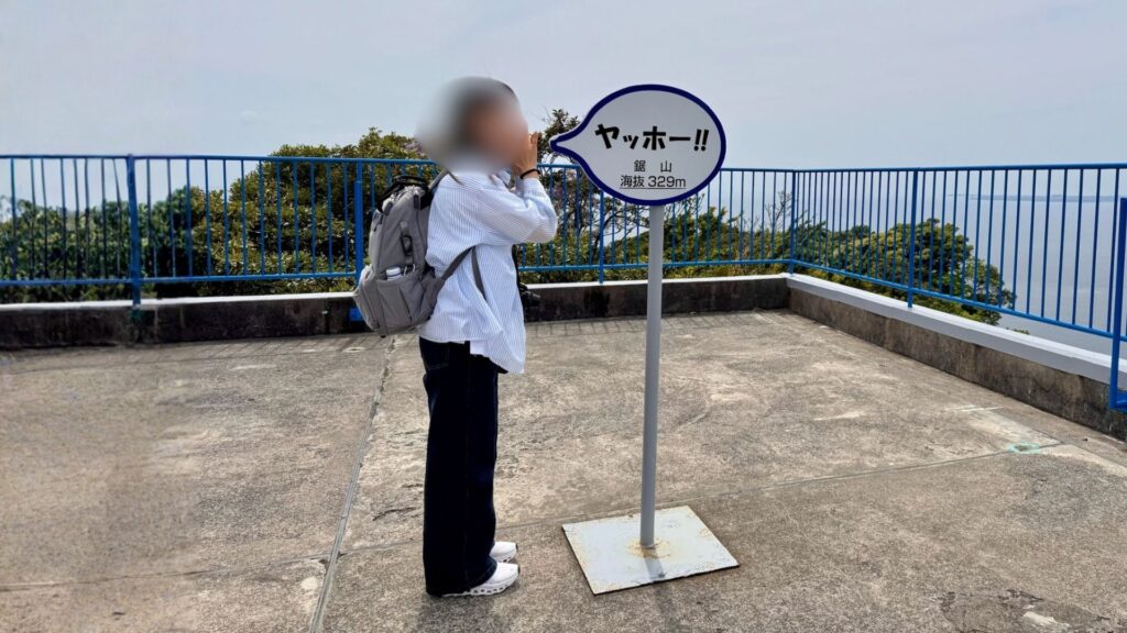 鋸山山頂の「ヤッホー」看板をスマホで撮影する様子