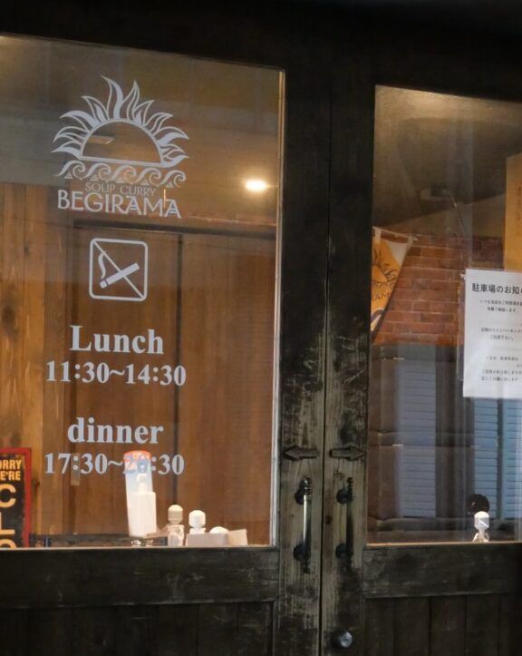 スープカレーベギラマの店舗入口とランチ・ディナーの営業時間表示