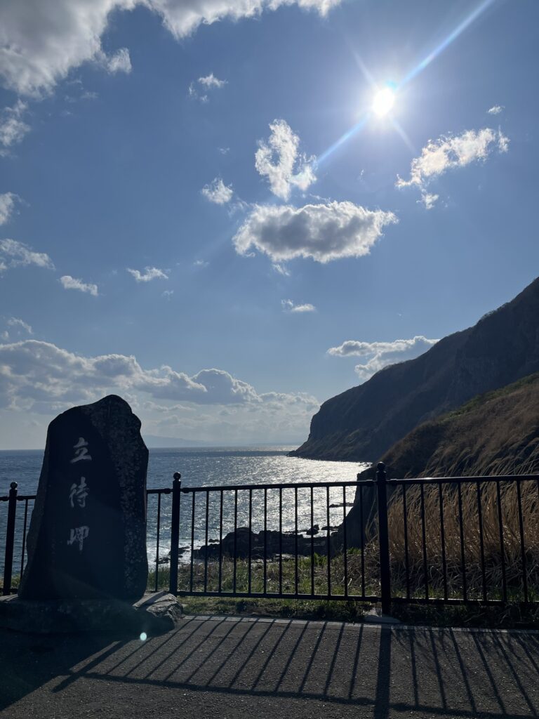 立待岬の石碑越しに広がる断崖と海の景色