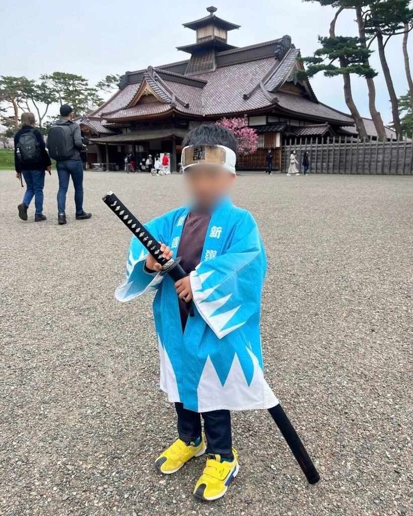 新選組の衣装を着て刀を持つ子ども、背景に五稜郭内の歴史的建造物